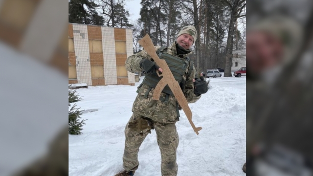 Ukrainian TV host Roman Vintoniv dressed in camouflage and holding a gun to fight the war