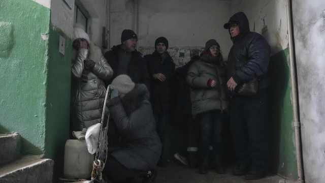 People seek cover from shelling inside an entryway to an apartment building in Mariupol, Ukraine.