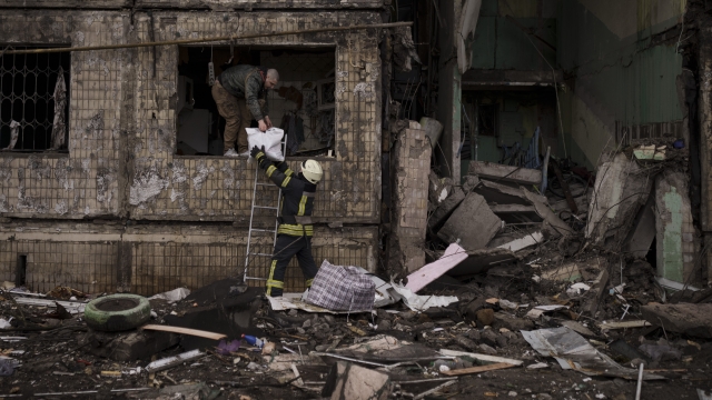 A Ukrainian firefighter helps a man remove belongings from a destroyed building
