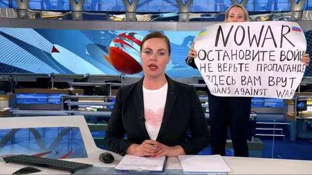 A Russian state TV employee holds a sign in protest on a Russian news show
