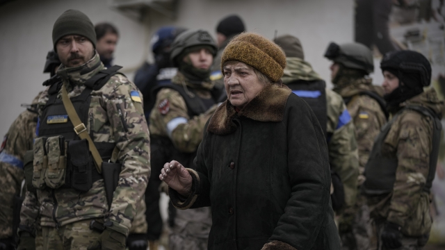 A woman walks by Ukrainian servicemen.