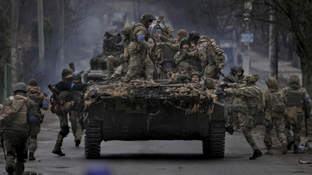 Ukrainian servicemen climb on a fighting vehicle outside Kyiv, Ukraine