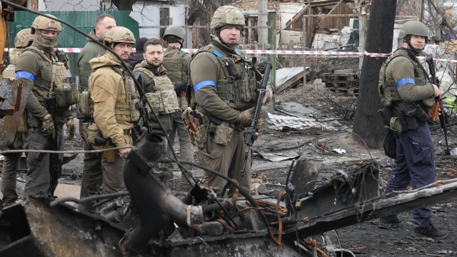 Ukrainian President Volodymyr Zelenskyy, center left, examines the site of a recent battle in Bucha.