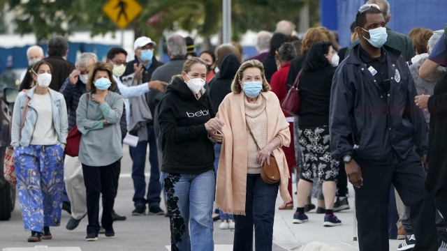 People in masks arrive at a hospital to receive the COVID-19 vaccine