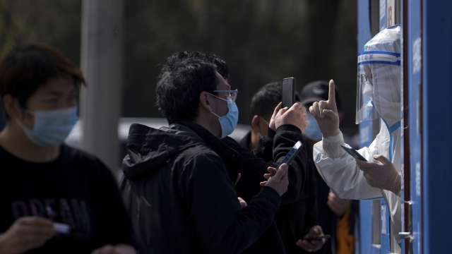Shanghai residents wearing face masks talk to a health worker
