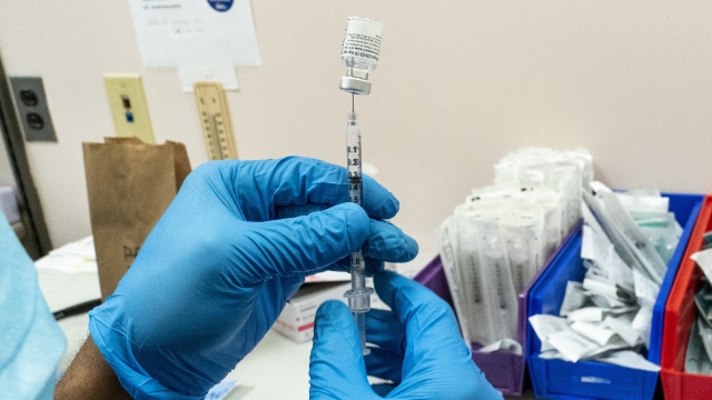 A health worker uses a syringe to draw a dose of a COVID-19 vaccine.