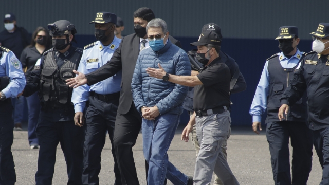 Former Honduran President Juan Orlando Hernandez, center, is taken in handcuffs to a waiting aircraft