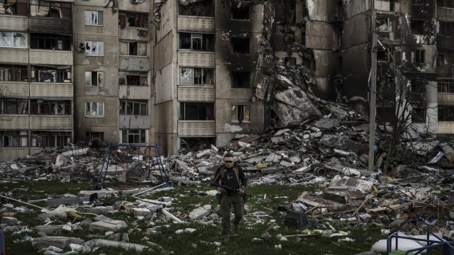 A Ukrainian serviceman walks amid the rubble of a building damaged by Russian forces.