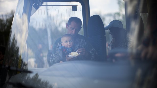 A man feeds a child as they arrive by bus at a reception center for displaced people in Zaporizhzhia, Ukraine
