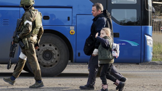 A Russian Army serviceman escorts Ukrainian civilians