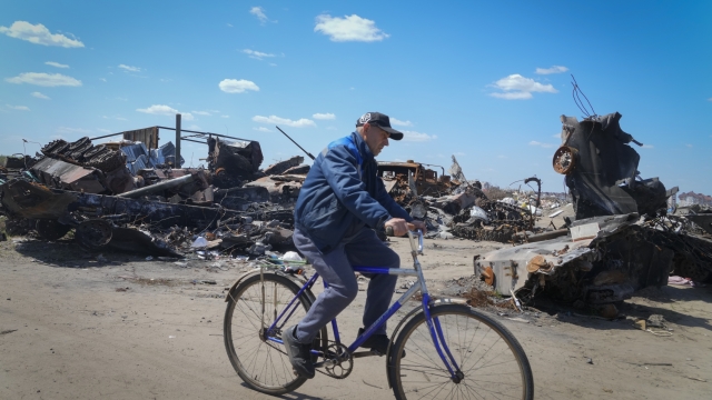 A local residence rides a bike past a destroyed Russian military vehicle in Bucha.