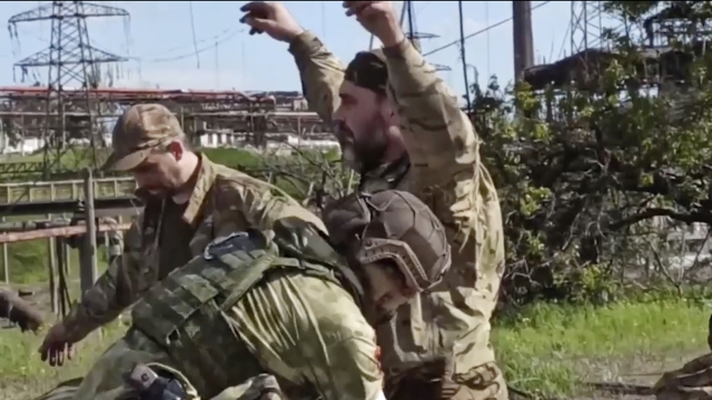 Russian servicemen frisk Ukrainian servicemen.