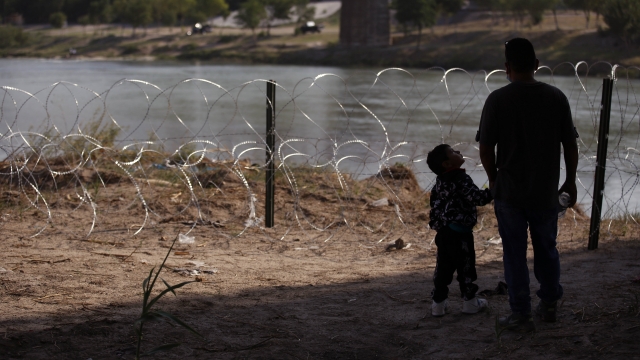 Man and child stand along the U.S.-Mexico border