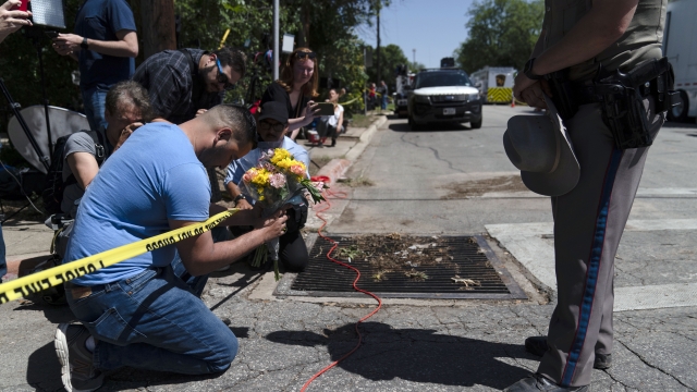 Joseph Avila, left, prays while holding flowers honoring the victims killed in Tuesday's shooting at Robb Elementary School