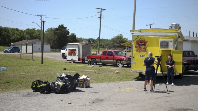 News crews film at the scene of a fatal shooting that happened at a Memorial Day event in Taft, Okla.