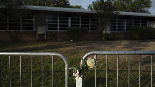 A rose with a message hangs on a barricade at Robb Elementary School in Uvalde, Texas