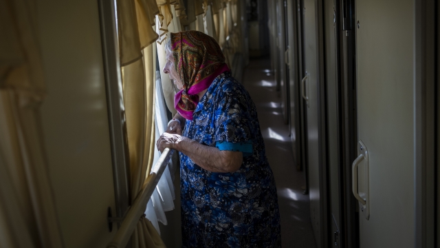 An elderly woman looks out the window in Ukraine