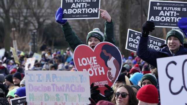 Anti-abortion protesters hold signs.