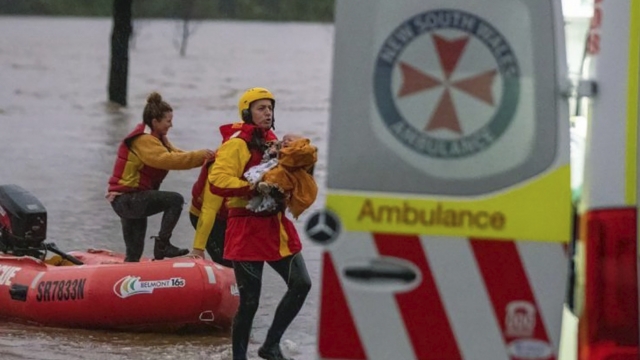 Emergency worker carries a baby from flood waters