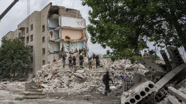 Rescue workers stand on the rubble at the scene in the after math of a missile strike that hit a residential apartment block