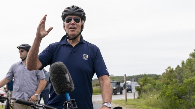 President Joe Biden speaks to members of the media as he goes on a bike ride.