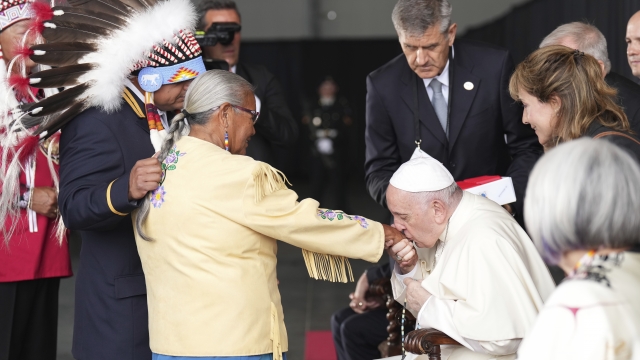 Pope Francis kisses hand to Canadian Indigenous woman.