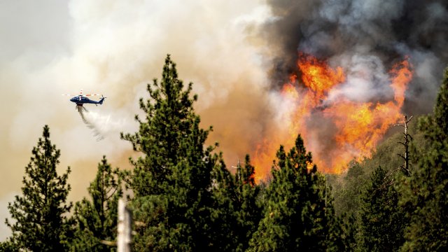 A helicopter drops water while battling the Oak Fire in Mariposa County