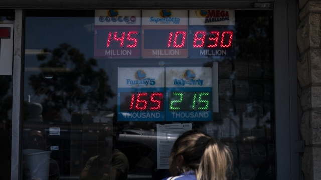 A woman peeks through the window of a liquor store while waiting in line to purchase a Mega Millions lottery ticket.