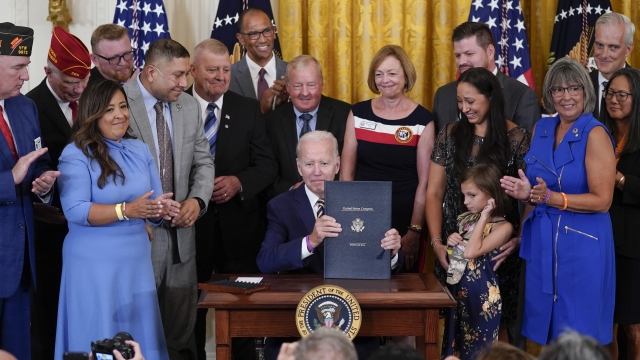 President Joe Biden holds the "PACT Act of 2022" after signing it during a ceremony in the East Room