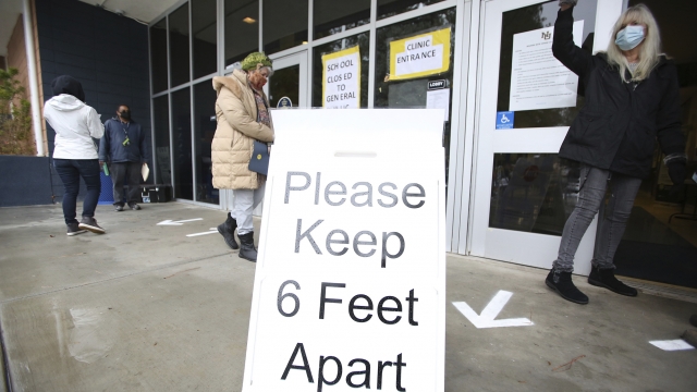 A sign asks those getting vaccinated to keep 6 feet apart during a vaccination event