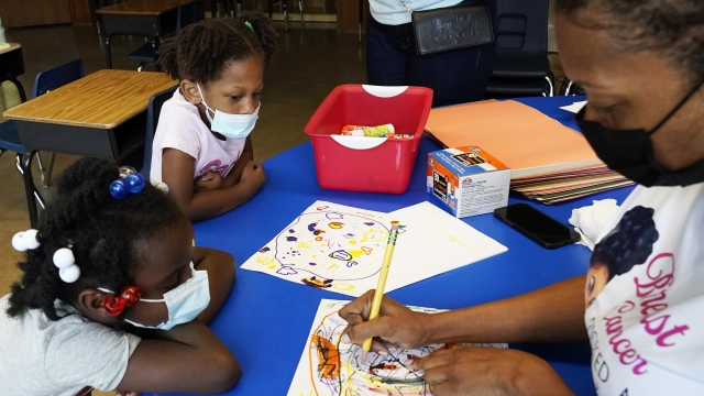 Laiah Collins, 4, and Charisma Edwards, 5, work with Davetra Richardson in a classroom
