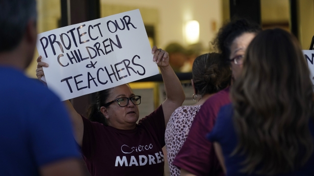 Parents and family of students hold protest signs during a special meeting