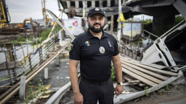 Ukrainian police officer Ruslan Huseinov stands on a destroyed bridge in the city of Irpin