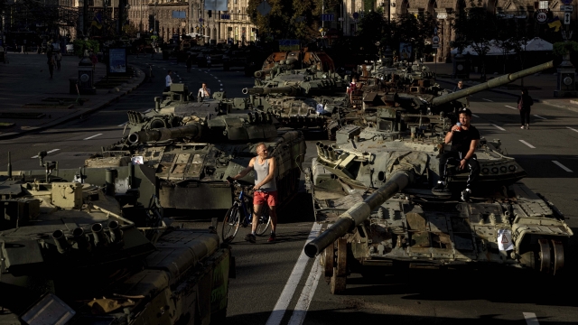 People walk around destroyed Russian military vehicles installed in downtown Kyiv, Ukraine.
