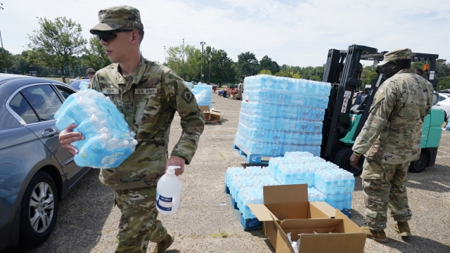 Mississippi National Guardsmen carry cases of drinking water.
