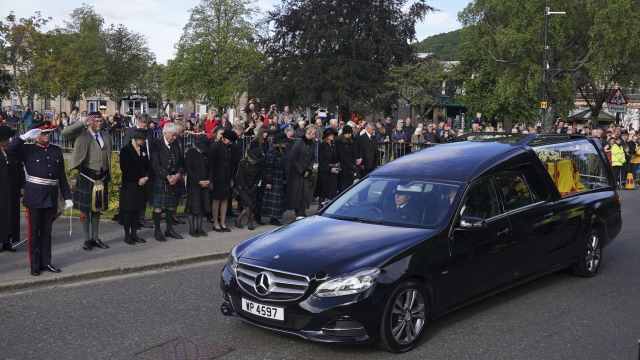 Members of the public line the streets in Ballater, Scotland, as the hearse carrying the coffin of Queen Elizabeth II passes
