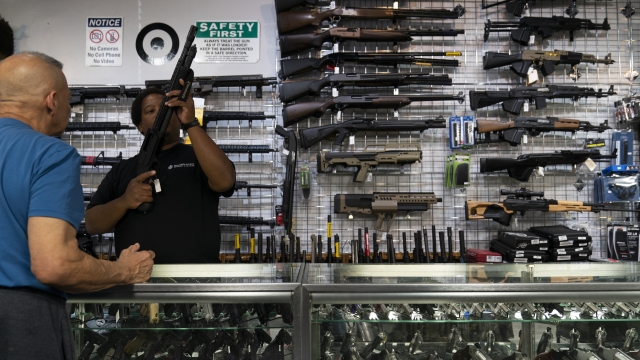 A gun store employee shows a gun to a customer.