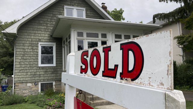 A "sold" sign is posted outside a home.