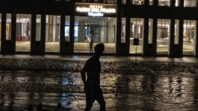 A man walks through a flooded street in front of a hotel powered by an oil generator during a blackout in Havana, Cuba