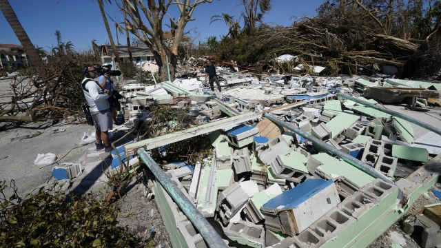A TV news crew works in debris on Sanibel Island