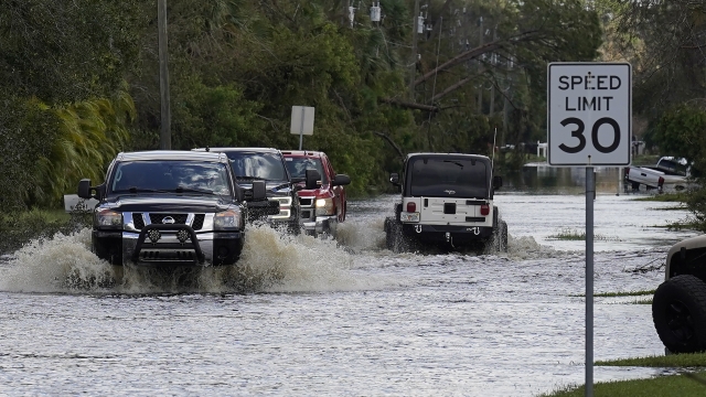 Residents drive through a flooded neighborhood Tuesday, Oct. 4, 2022, in North Port, Fla.