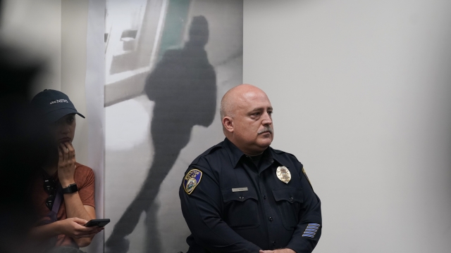 Stockton Police Public Information Officer Joseph Silva stands next to an enlarged image of a person of interest.