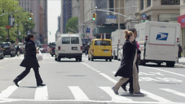 People walk across a New York City street.