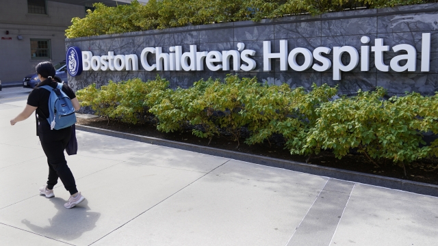 A woman walks past a sign outside the Boston Children's Hospital