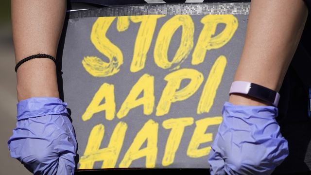 woman holds a sign and attends a rally to support stop AAPI (Asian Americans and Pacific Islanders) hate