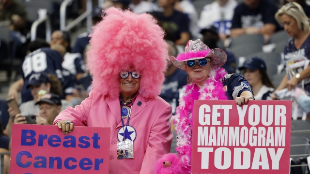 Dallas Cowboys fans hold signs supporting cancer awareness before the first half of a NFL football game