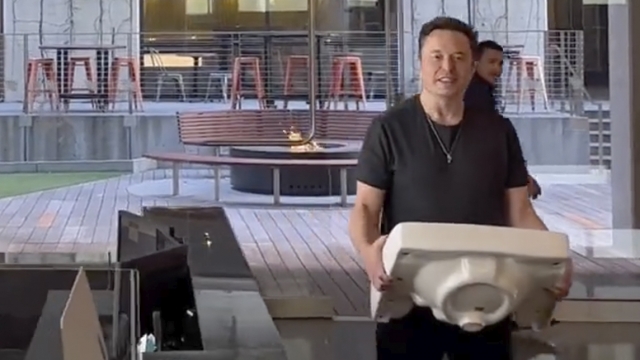Elon Musk carries a sink through Twitter headquarters.