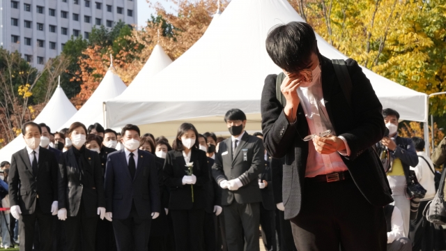 A mourner wipes his tear as he pays a silent tribute for victims of a deadly accident following a Halloween festival