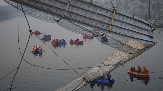 Rescuers in boats search in the Machchu river in India next to a cable suspension bridge that collapsed