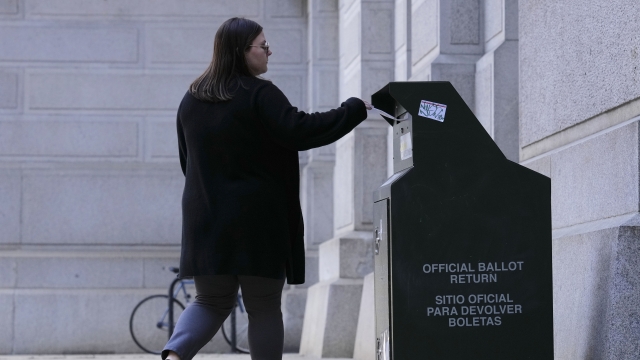 Woman drops off a ballot at an election ballot return box.